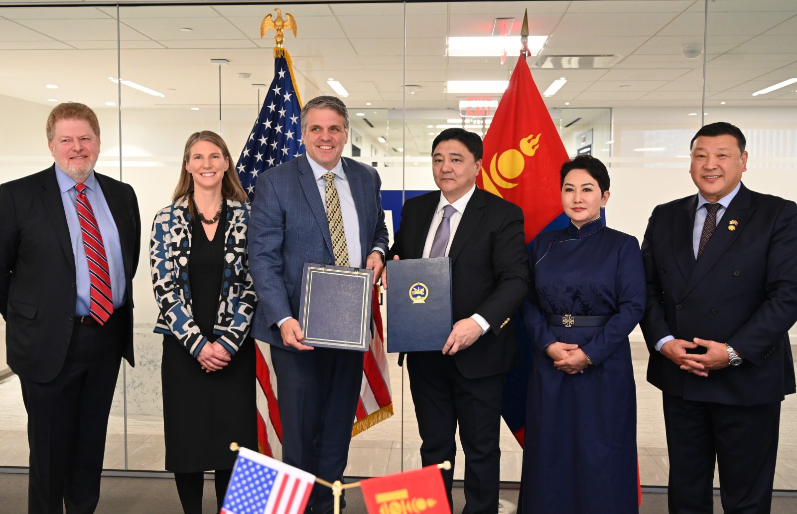 Six people in front of U.S. and Mongolia flags. USTDA Dep. Director and Grantee hold signed grant documents.