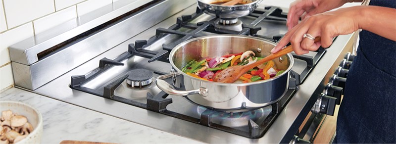 person cooking vegetables in a pan 