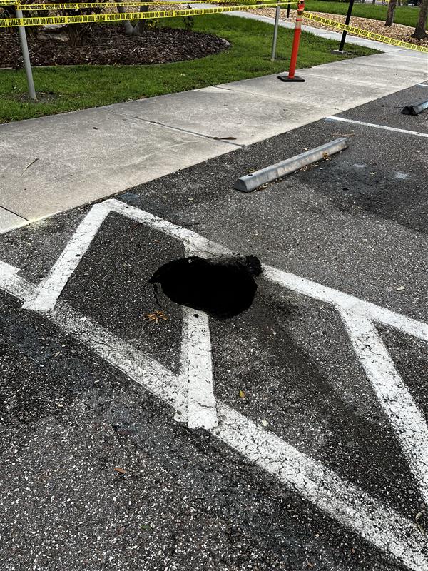 Small hole in the asphalt of a parking lot.