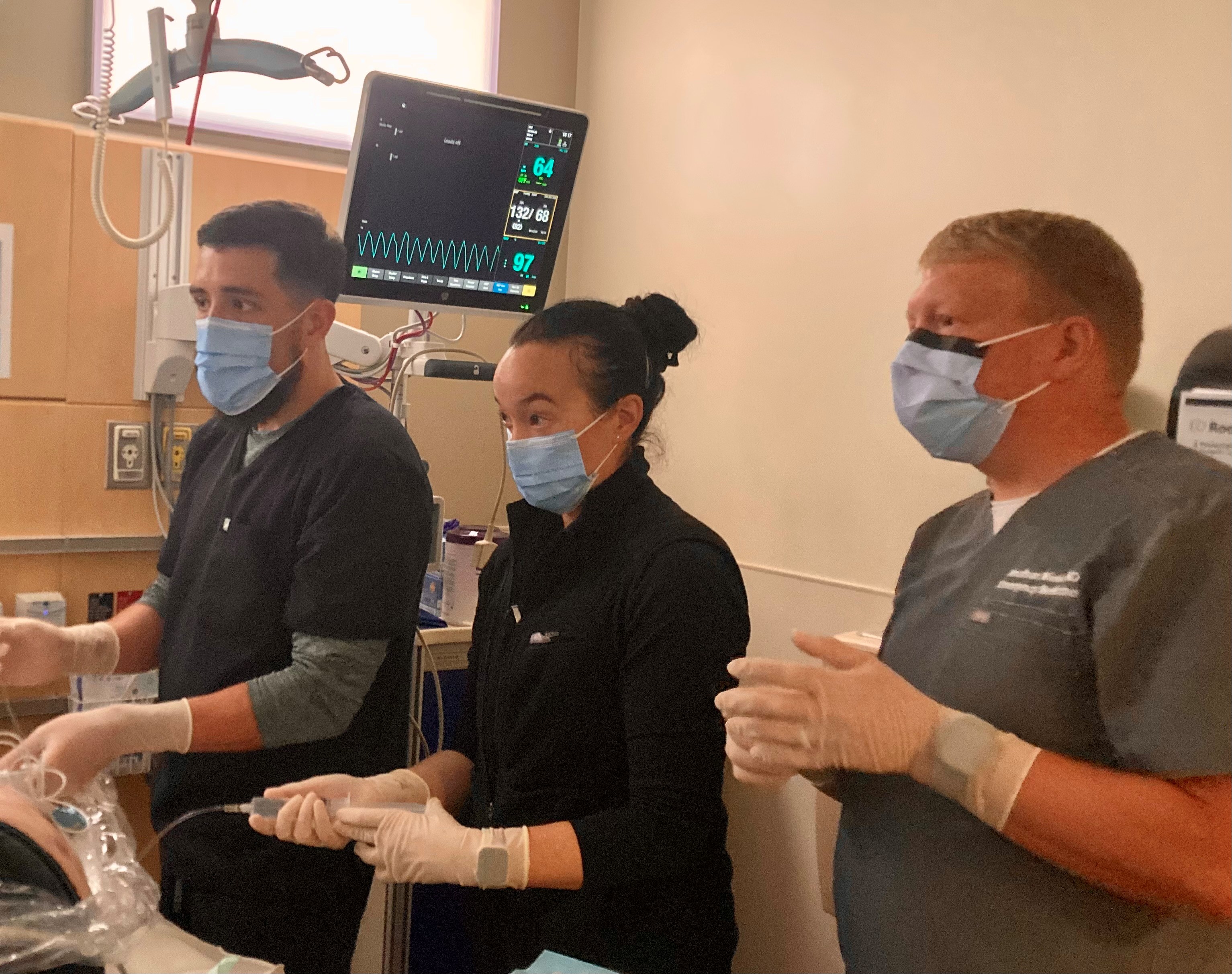 Residents, doctor working in an emergency room training scenario.