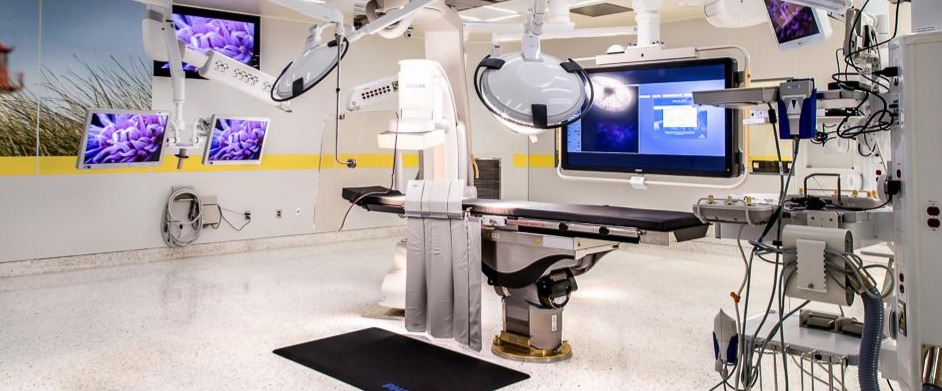 Modern surgical room with multiple monitors, surgical table, and medical equipment.