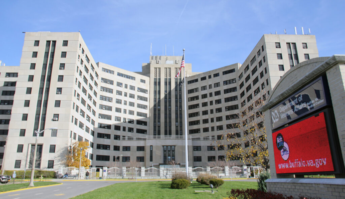 Large white building with many windows and a red signboard.