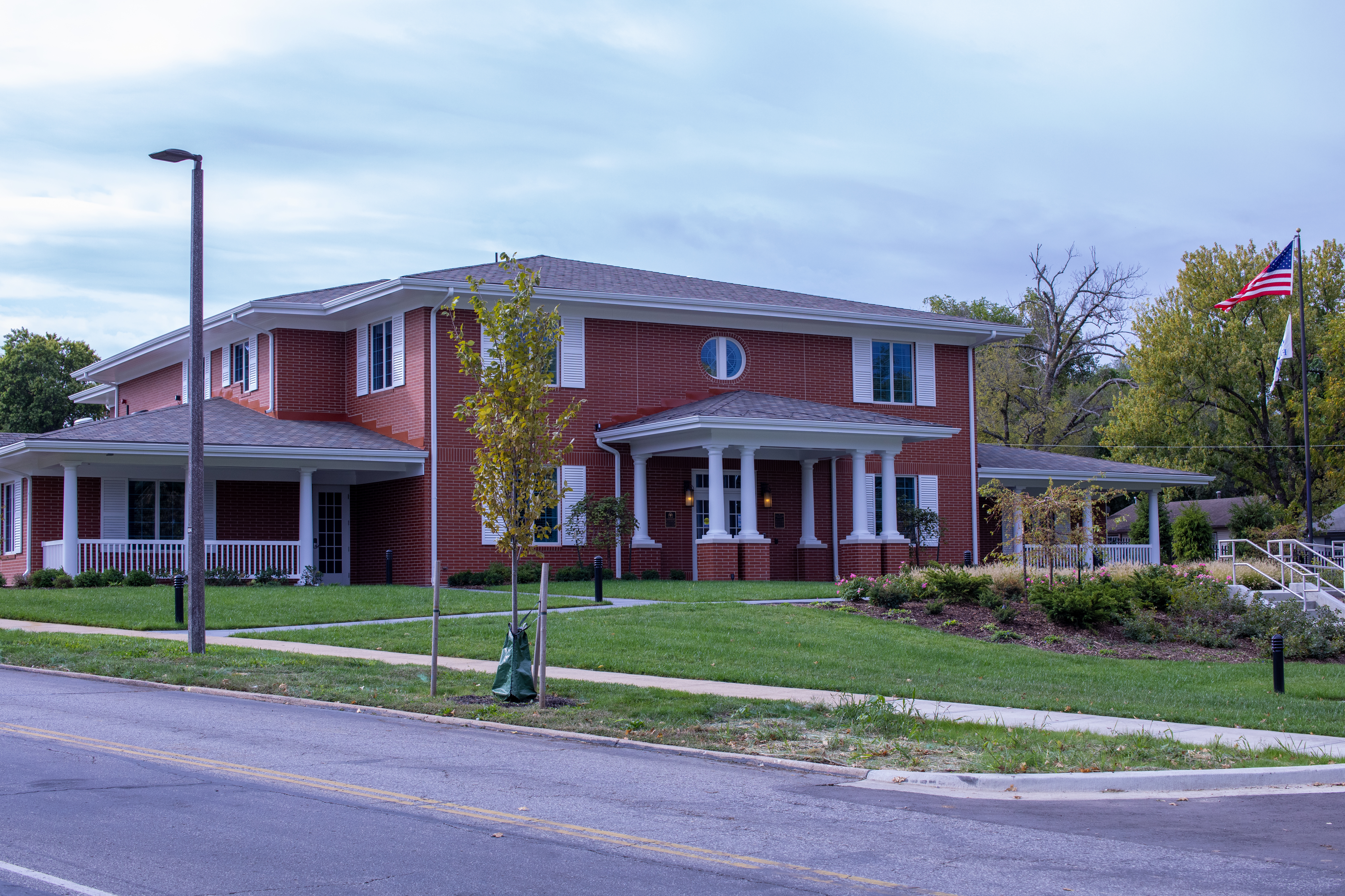 Red building with white trim and columns, set in a grassy area with an American flag.