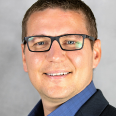 Man with dark-framed glasses, medium-navy blue button-down shirt and dark blue suit jacket.