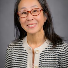 Portrait of a woman in a black and white striped blazer, smiling.