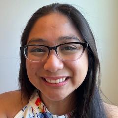 A smiling woman with glasses and a colorful top.