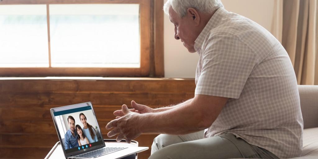 Happy elderly man holding video call with family on laptop