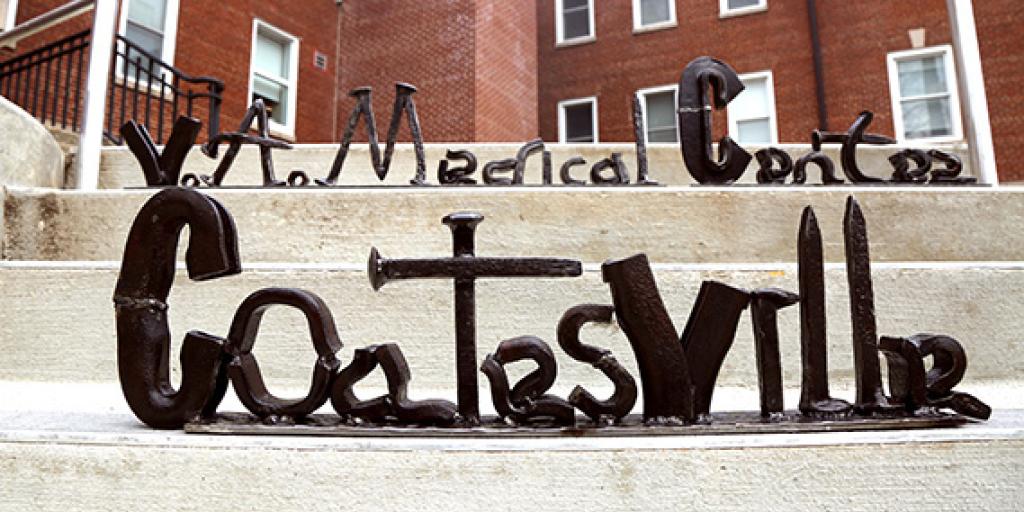 Iron twisted to form the words “Coatesville VA Medical Center” set on steps outside a building. 