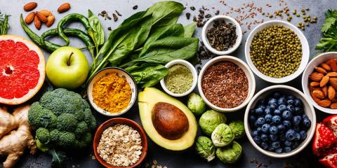 Colorful fruits and veggies such as broccoli, spinach, Granny Smith apples, blueberries, ruby red grapefruit and more displayed neatly on a table.