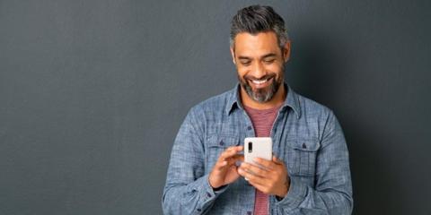 Photo of smiling Veteran with smartphone.