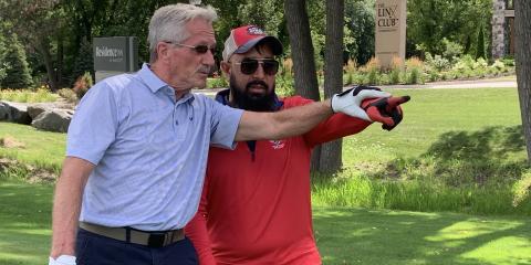 John Harvey, left, helps blind Veteran A.J. Mohammed line up his tee shot.