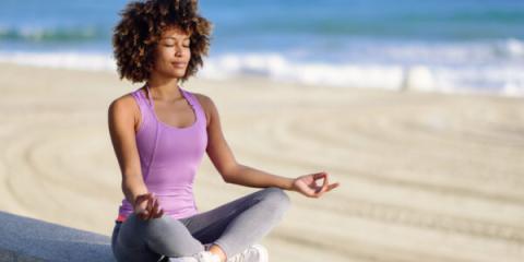 A young, Black female does yoga on the beach.