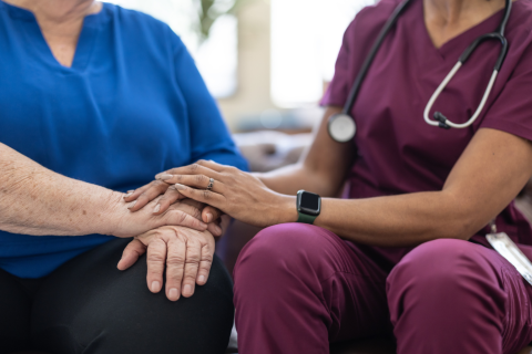 A health care professional places their hands on top of a patient's hands.