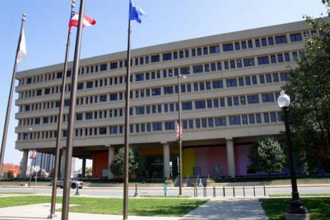 The Minton–Capehart Building is a large multi-story building across from the flagpoles. It has many windows & a colorful mural that wraps around it.