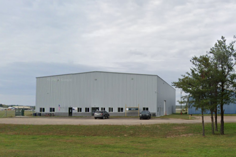 A large grey building in a rural area 