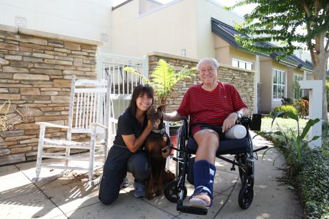 Pictured in photo: Recreational Therapist Felicity Ruiz, Facility Dog Autumn, and Army Veteran David Ronco enjoying sunshine and fresh air at the CLC
