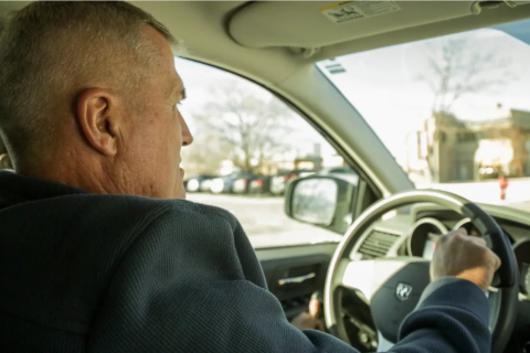 Man driving a car, seen from behind.
