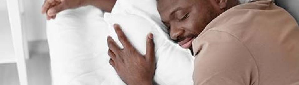 A man is sleeping and hugging his pillow