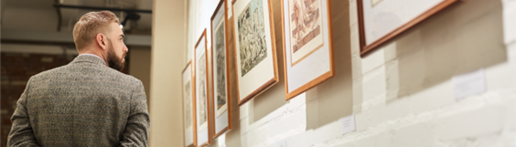 Man in hallway looking at art on the wall.